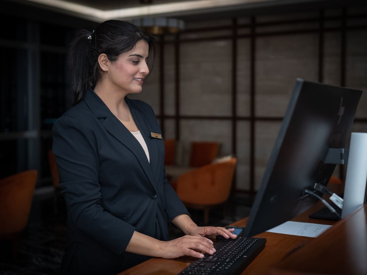 A hotel receptionist working at the front-desk computer