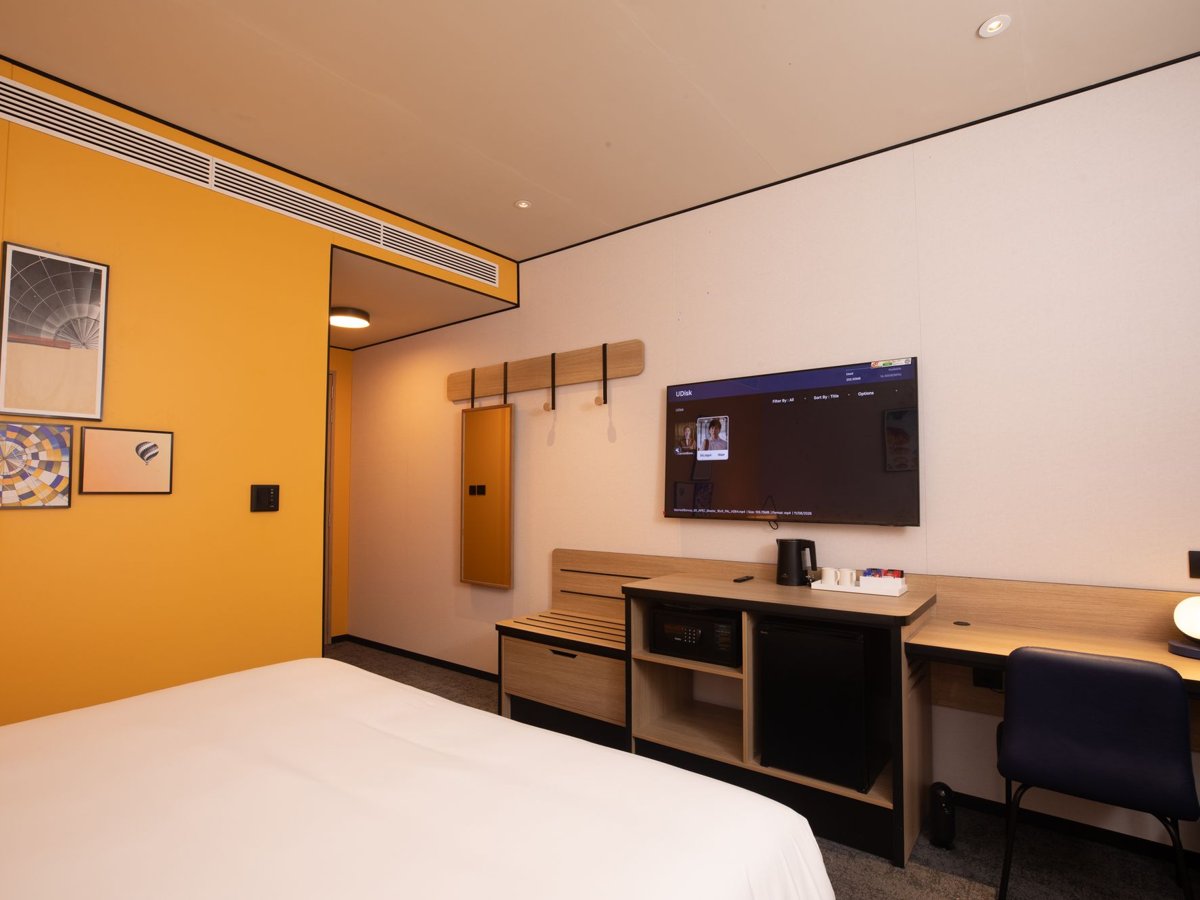 A hotel guest room with a wall-mounted TV